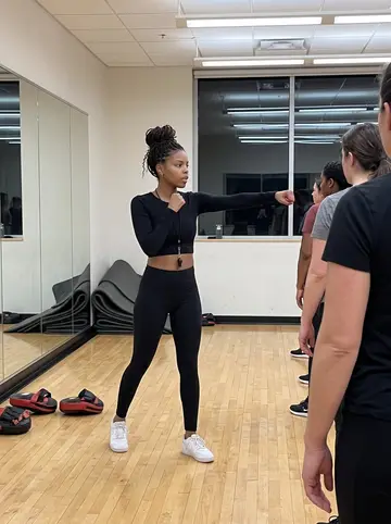Nia, AI character: the campus rec center group-fitness room during her six o'clock women's boxing class, mirrors and pads on…