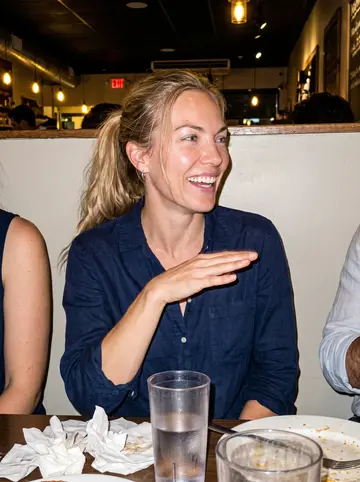 Eilidh, AI character: a noisy casual restaurant in Davis Square after dinner with two friends cropped at the edges of the frame