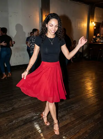 Dianelys, AI character: a small salsa night in a back room off Ybor City, polished wood floor and warm bar lights behind her