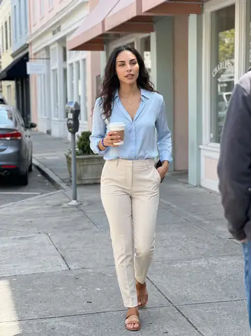 Antigoni, AI character: King Street in Charleston after a vendor meeting, walking past pastel storefronts with a takeaway coffee