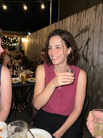 Lydia, AI character: a crowded back patio bar in Southeast Portland after workshop, string lights and friends cropped around…