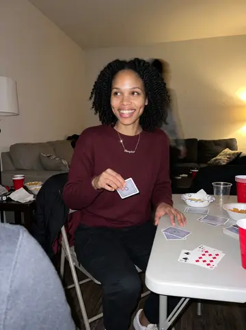 Ashanti, AI character: her cousin’s Decatur apartment during spades night, folding table crowded with cards, plastic cups and…