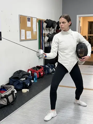 Verena, AI character: a small fencing club in Denver on Tuesday night, narrow piste, gear bags along the wall