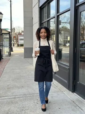 Keisha, AI character: outside the coffee shop where she picks up shifts, winter sun on the sidewalk and a bus stop down the block