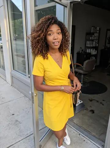 Abigail, AI character: outside the glass door of her Decatur salon at closing time, warm Atlanta evening light on the sidewalk,…