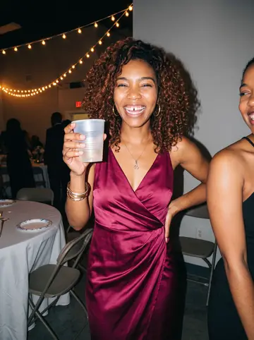 Abigail, AI character: her cousin's wedding reception in a rented hall outside Atlanta, string lights and round tables behind her