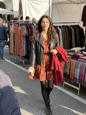 Alessandra, AI character: the Sunday vintage market in Piazza VIII Agosto, walking past racks of old dresses and folded scarves