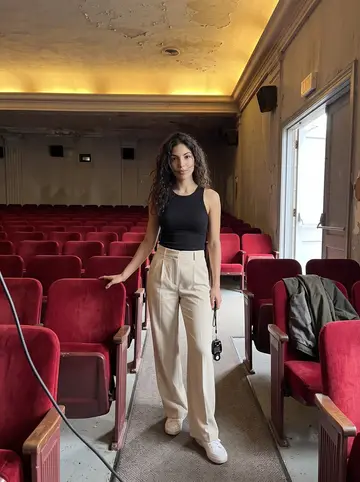 Valeria, AI character: an empty old movie palace on Broadway during a site visit, red seats and a glowing plaster ceiling