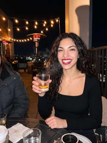 Valeria, AI character: a downtown LA rooftop bar in December with friends from the firm, heaters glowing