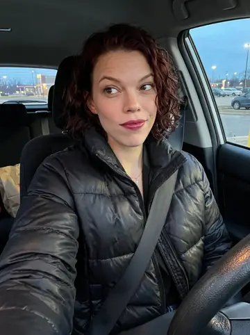 Brooklyn, AI character: parked car outside a drive-thru on a cold Cincinnati evening, paper bag on the passenger seat