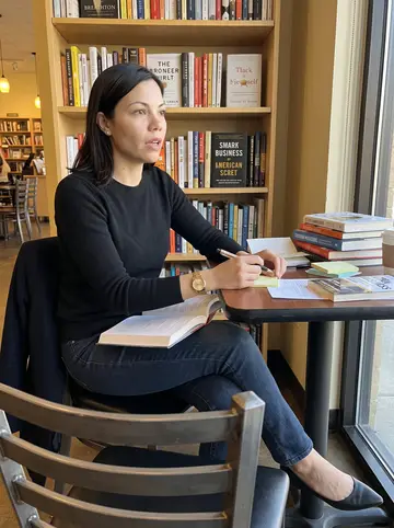 Natalie, AI character: a small independent bookstore cafe in Houston where she is marking up the firm's reading list on a Saturday