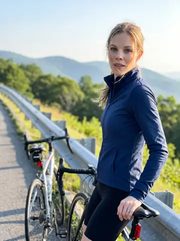 Shelby, AI character: Blue Ridge Parkway pull-off just after sunrise, her road bike Doris leaned against the guardrail behind her
