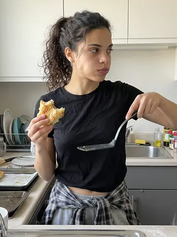 Jelena, AI character: shared apartment kitchen near campus, tray of homemade burek cooling on the counter