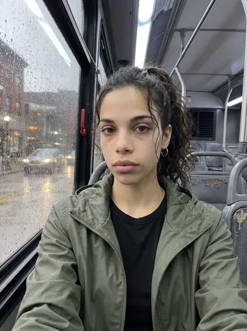 Jelena, AI character: Pittsburgh city bus window seat after a rainy class day, wet streetlights reflected in the glass