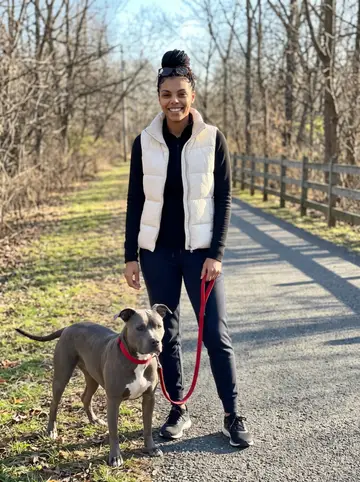 Shanice, AI character: the university track in Durham just after sunrise, leaning against the rail by the sprint lanes with the…