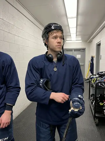 Maik, AI character: host family's garage in suburban Saskatoon, the closed garage door marked by tennis-ball scuffs, hockey…