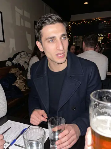 Jonny, AI character: a crowded Southie pub quiz table in December, pint glasses and score sheets on the table