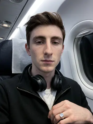 Conal, AI character: an indoor practice rink late at night, empty seats and scuffed boards behind him