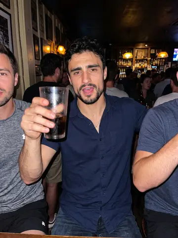 Modesto, AI character: a crowded sports bar near Queen Street after a summer charity street hockey game, teammates cropped around him