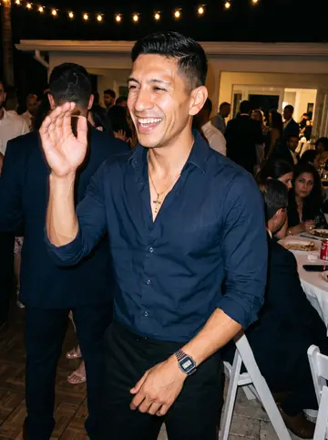 Yoandy, AI character: cousin's wedding reception in Miami, crowded dance floor with warm string lights and family tables behind him
