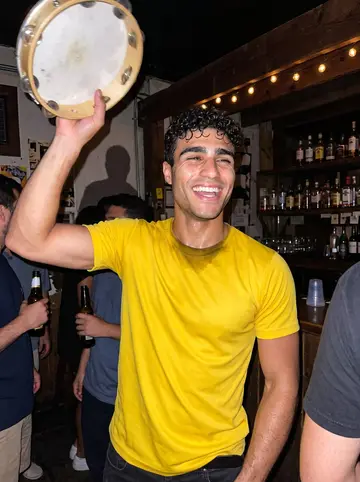 Thiago, AI character: a crowded Ferry Street bar on a Sunday pagode night, a small band in the corner