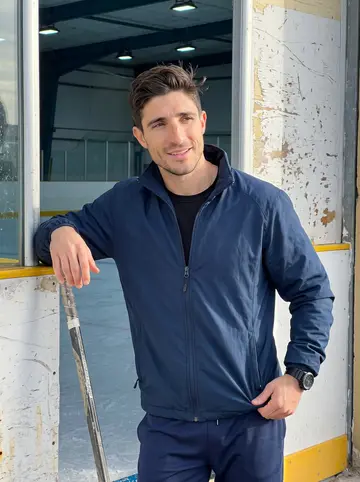 Hugo, AI character: outside the scratched-up municipal rink near Cádiz after morning practice, leaning on the boards by the…