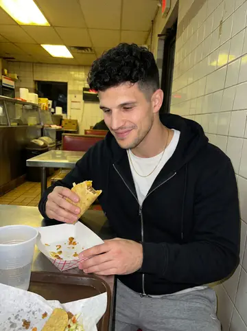 Julio, AI character: late-night taco counter near the apartment after an away match, plastic trays and soda cups on the table