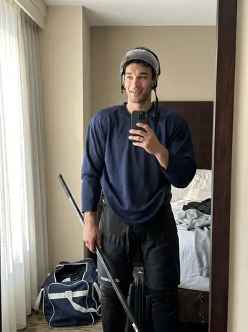 Jaxon, AI character: outside the practice rink in the new city, beside the arena doors after morning skate, with snow piled…