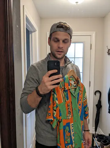 Garrett, AI character: a crowded Ohio thrift store aisle between racks of old shirts, midday