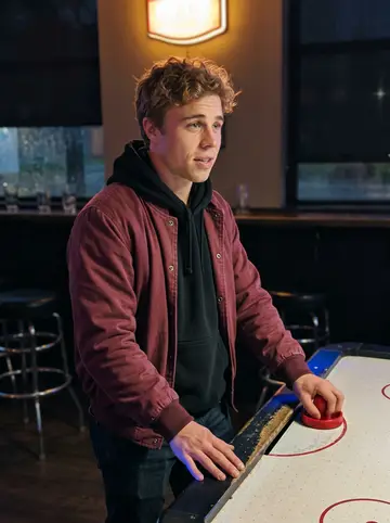 Michael, AI character: a dim college bar near campus with an air hockey table behind him and rain shining on the front windows