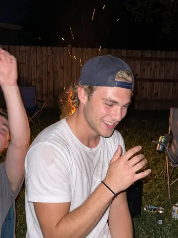 Teddy, AI character: a friend's backyard bonfire in Kingston in summer, teammates from home crowding around