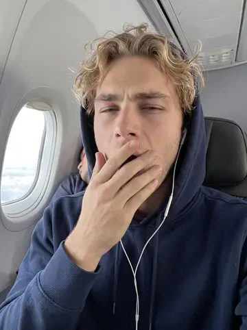 Teddy, AI character: a window seat on the team's early flight to a road game, grey clouds outside