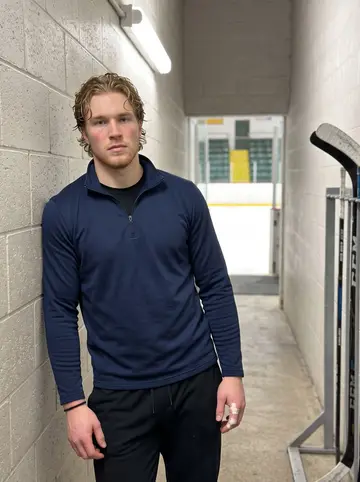 Brody, AI character: the concrete tunnel behind the bench at Cheel Arena after a home game, sticks racked on the wall