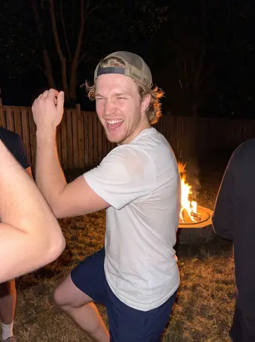 Brody, AI character: a friend's backyard bonfire in Kingston in summer, teammates from home crowding around