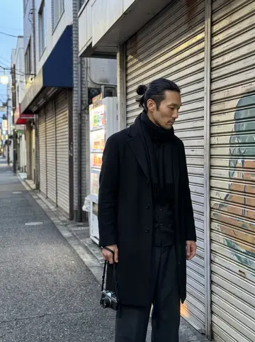 Ryo, AI character: a quiet Tokyo shopping street before sunrise, closed metal shop shutters along the sidewalk and a small…