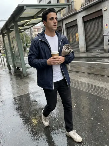 Íñigo, AI character: wet Bilbao street near the tram stop after a long shift, reflective pavement and closed shopfronts behind him