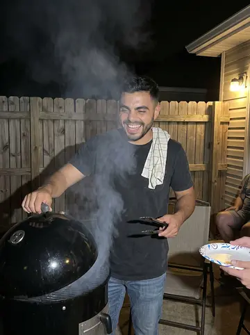 Santi, AI character: his backyard at night, a barrel smoker, folding chairs and neighbors with paper plates