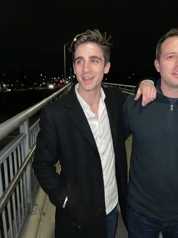 Rhys, AI character: the lawn of a farm wedding outside Lexington, white chairs and string lights in the background, evening