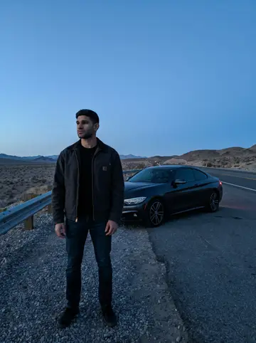 Lance, AI character: empty desert highway overlook outside Las Vegas before dawn, his dark coupe parked a few yards back