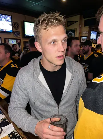 Carl, AI character: a crowded Pittsburgh sports bar during a Steelers preseason game, TV glow and black-and-gold jerseys…