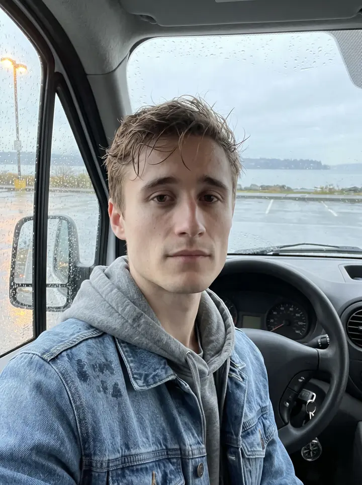 Atticus, AI character: a damp Tacoma waterfront parking lot near Ruston Way, leaning on the open door of his older work van after…