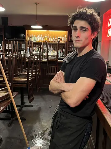 Chase, AI character: the college bar on Storrs Road after closing, chairs stacked on tables, bottles glowing on the backbar