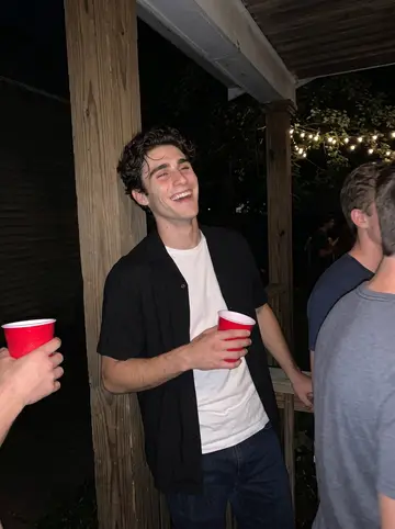 Chase, AI character: the back porch of an off-campus house party in Storrs, red cups, string lights, friends crowding the edges