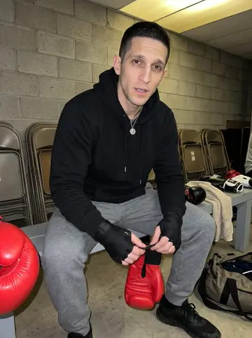 Predrag, AI character: church basement boxing room after class, empty folding chairs stacked near the wall and gloves on a bench