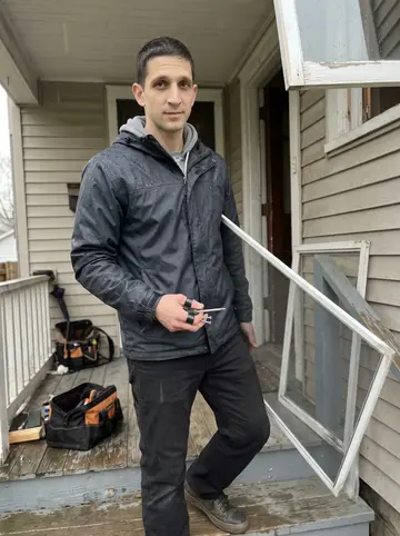 Predrag, AI character: front porch of an older Cleveland duplex in light rain while he helps a neighbor fix a loose window frame