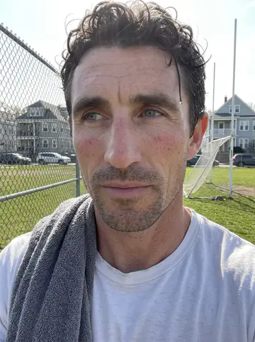Tadhg, AI character: the edge of a hurling pitch in Canton on a Sunday morning, a wooden bench, a gym bag and a hurley lying on…