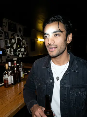 Joaquim, AI character: a small dim bar on Ferry Street in the Ironbound, wooden bar and bottles behind him, a winter night