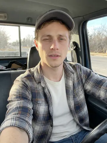 Carlos, AI character: driver seat of his old Chevy Silverado parked near a quiet Beaumont roadside on a clear winter Sunday