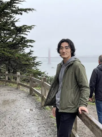 Wes, AI character: the Lands End trail in San Francisco on a foggy afternoon, cypress trees and the bridge faint behind