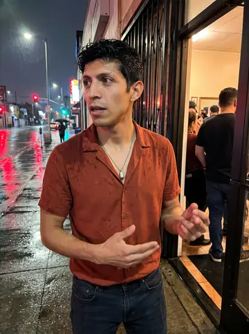 Raúl, AI character: outside a small salsa night in East LA, wet sidewalk reflecting neon and a doorway full of people behind him